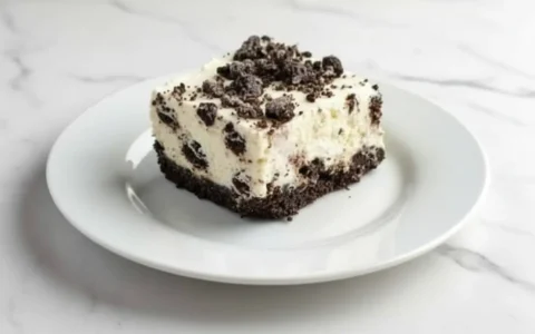 Slice of No Bake Oreo Cheesecake with cookie crust on a white plate.