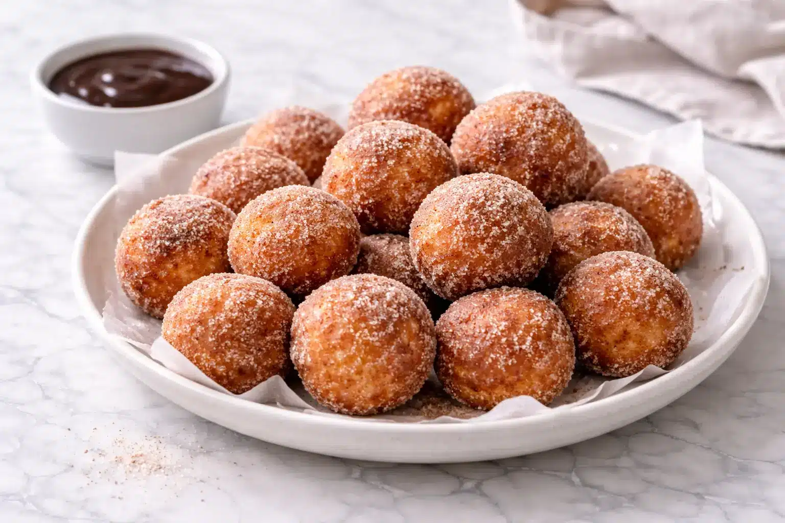 Churro Donut Bites Churro donut bites coated in cinnamon sugar on white marble surface