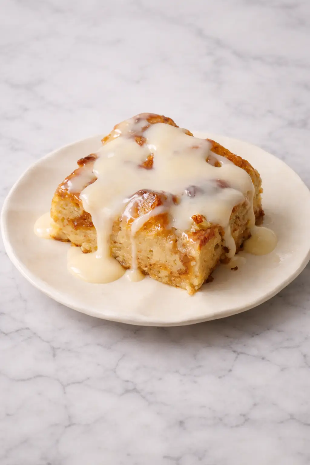 Delicious cinnamon bread pudding served with warm vanilla sauce, drizzled generously on a white plate—perfect homemade dessert close-up.