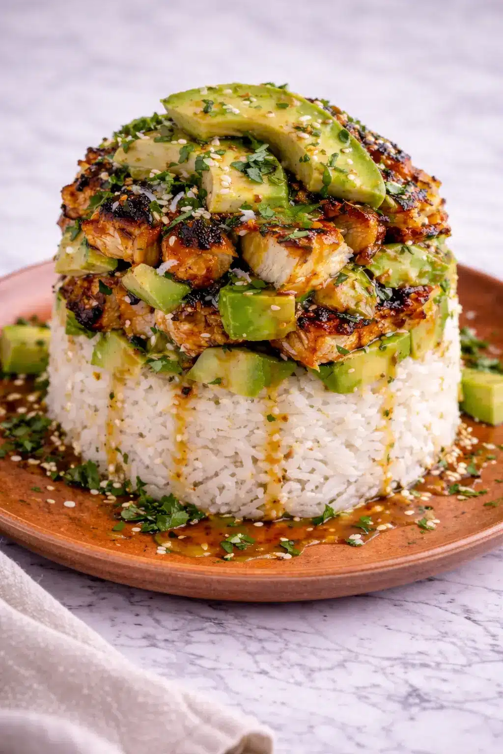 Honey Lime Chicken and Avocado Rice Stack layered with glazed chicken, avocado, and rice on a plate in a vertical view