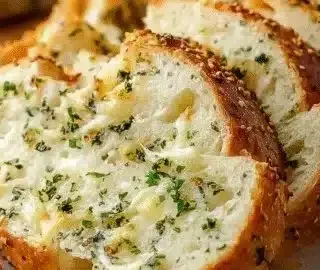 Loaf of Italian herb cheese bread topped with fresh herbs and cheese