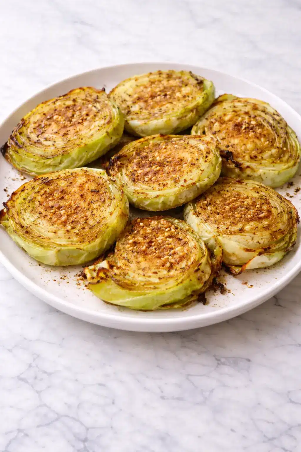Oven Roasted Garlic Cabbage Steaks Oven-roasted garlic cabbage steaks with crisp edges on a white plate