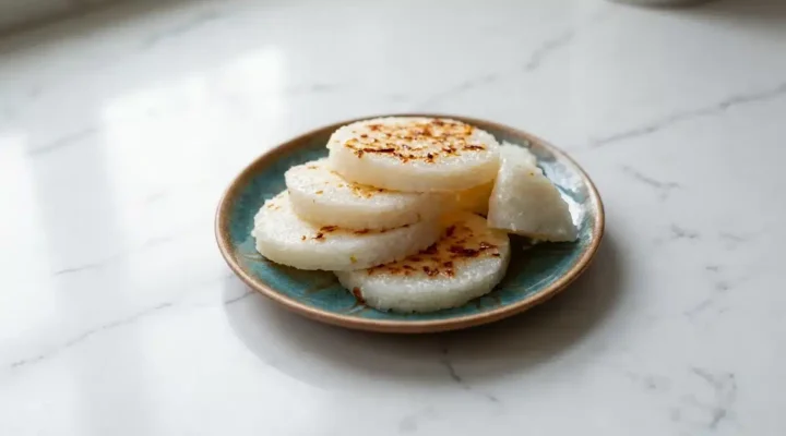 Photorealistic South Asian rice cake, freshly cooked and naturally plated on white marble, ready to serve with a home kitchen feel.