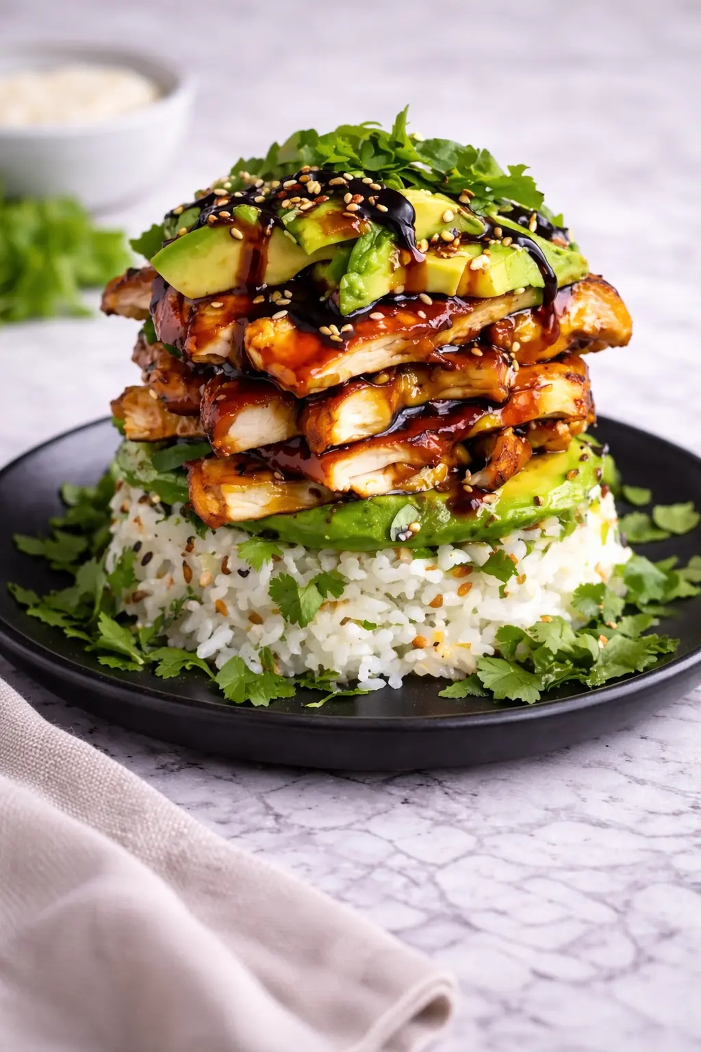 Teriyaki Chicken Avocado Rice Stack layered with glazed chicken, avocado, and rice on a plate in a vertical view
