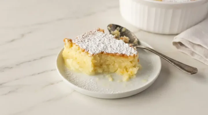Photorealistic Lemon Custard Pudding Cake, freshly baked, naturally plated, ready to serve on white marble, with natural light.