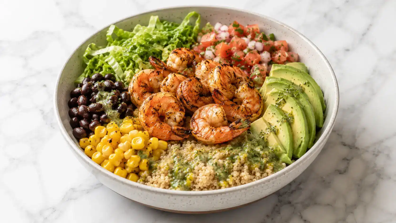 Healthy Shrimp Avocado Bowls with grilled shrimp, quinoa, avocado, black beans, corn, romaine lettuce, pico de gallo, and cilantro vinaigrette served in a ceramic bowl.